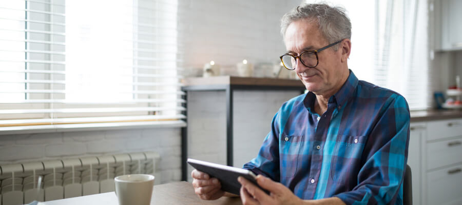 A Canadian man sitting down, looking at his tablet, to learn more about the CPP benefits that can boost his retirement income.