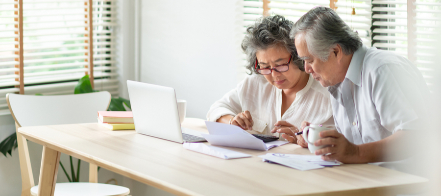 An older Asian couple punching in numbers at a table