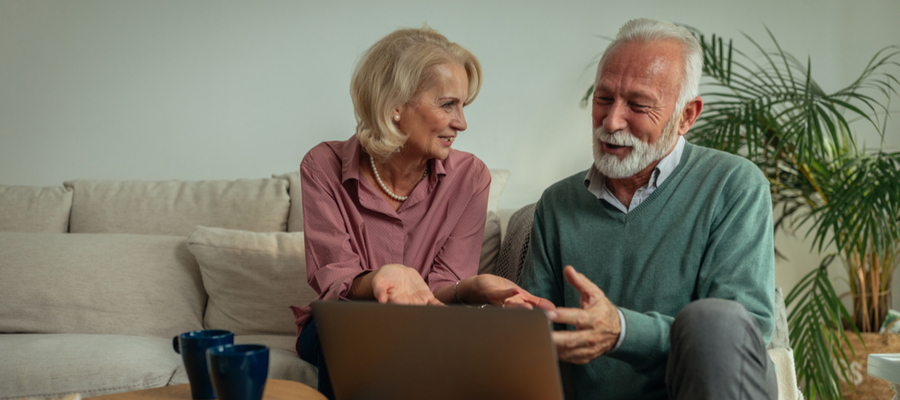 An older couple sitting on couch talking and laughing