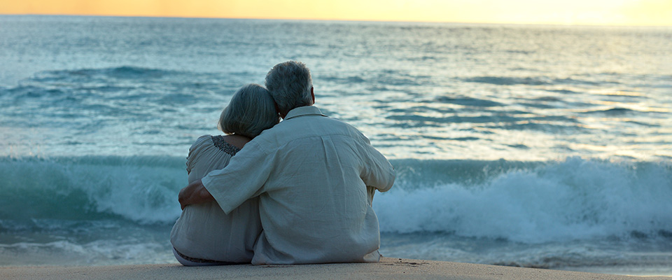 Older couple sitting at the beach on their late honeymoon defining the changing expectations from life partner in senior years.