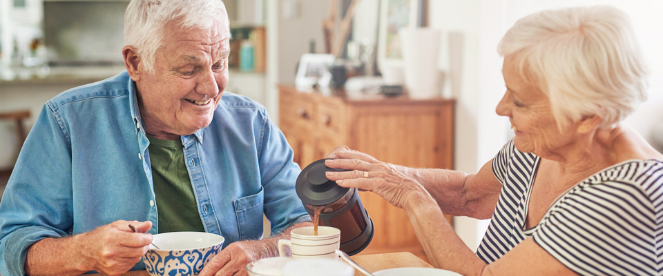 An older couple at the dining table discussing the growing demand for co-housing and how it can add to income after retirement.