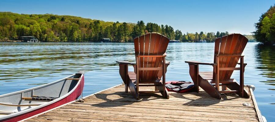 view of the lake and dock with two Muskoka chairs and a canoe