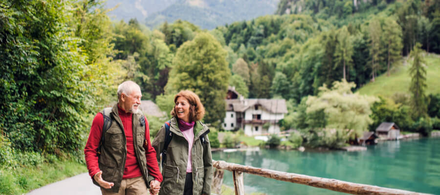 A senior pensioner couple hiking in nature, holding hands.