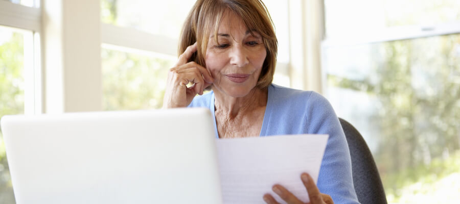 An older woman at a laptop looking at a document