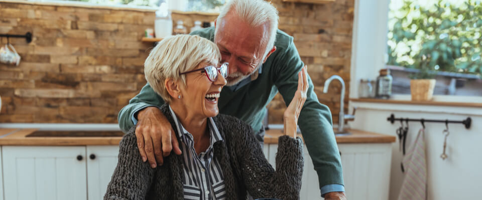 A husband leaning and whispering in his wife's ear laughing together