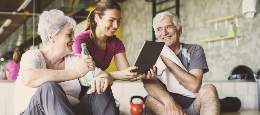 A woman showing her tablet with an older couple in exercise clothes