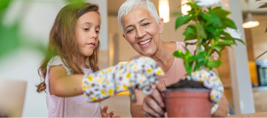 A grandmother planting a pot with her granddaughter
