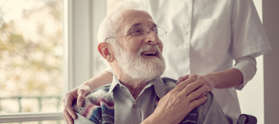 An older man looking up at his caregiver