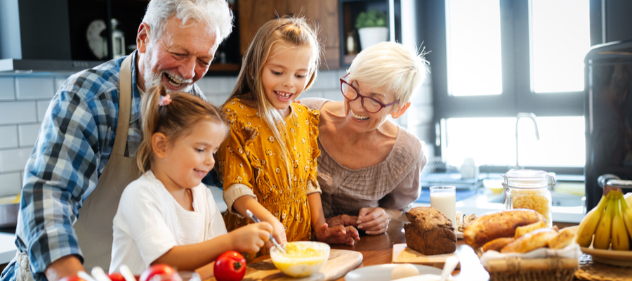 Grandparents with their two granddaughters baking in the kitchen together