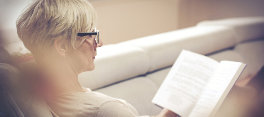 a side view of a woman sitting on a couch reading a book