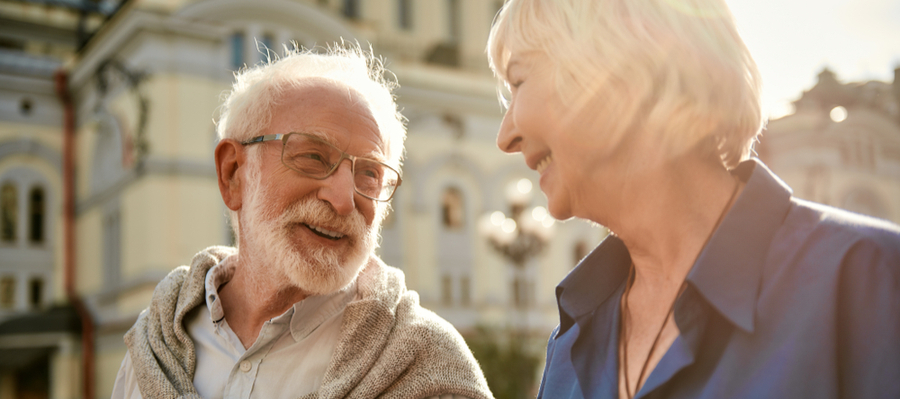 A couple walking in a European city smiling and looking at each other