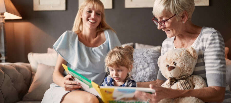 A grandmother and a mother reading a storybook to a little girl