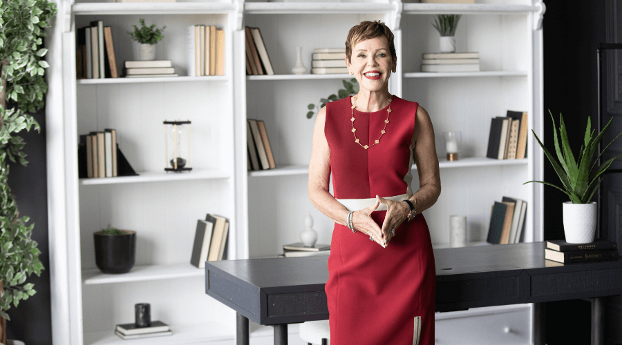 Pattie-Lovett-Reid-Standing-and-Smiling-In-Red-Outfit