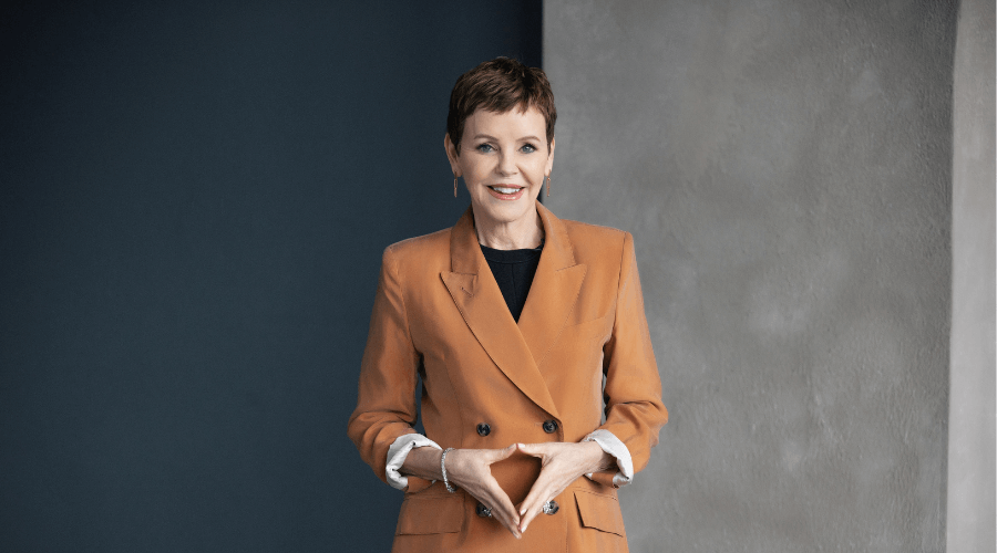 Pattie-Lovett-Reid-standing-and-smiling-in-orange-suit