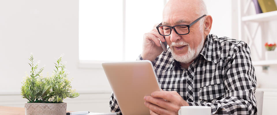 Older man talking on the phone and getting aware of the common fraud scams aimed at retirees and ways to protect themselves.