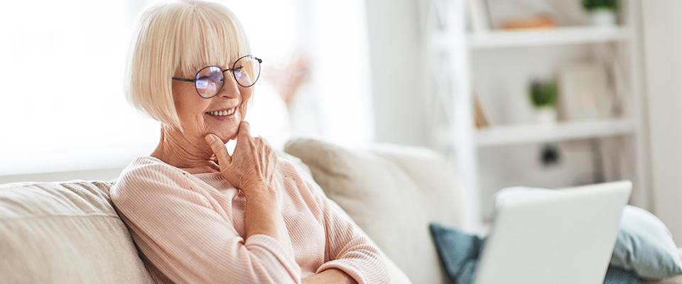 Older woman on her laptop reading how Reverse Annuity Mortgage helps a wide variety of people to relieve their financial worries.