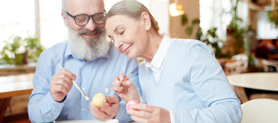 Older couple painting eggs for Easter with paintbrushes