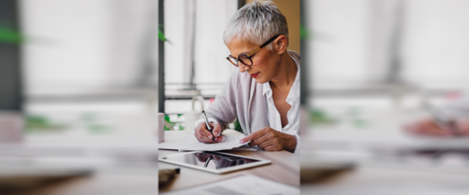 An older woman at her workplace past her retirement age while welcoming the changing trends in society that will support them.