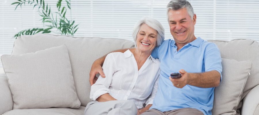 Happy older couple sitting on the couch watching TV