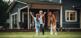 an-elderly-couple-playing-with-their-granddaughter-in-front-of-their-home