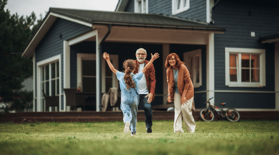 an-elderly-couple-playing-with-their-granddaughter-in-front-of-their-home