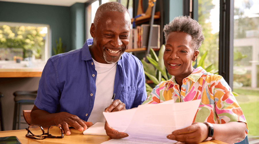 an-elderly-man-and-woman-smiling-as-they-review-their-taxes