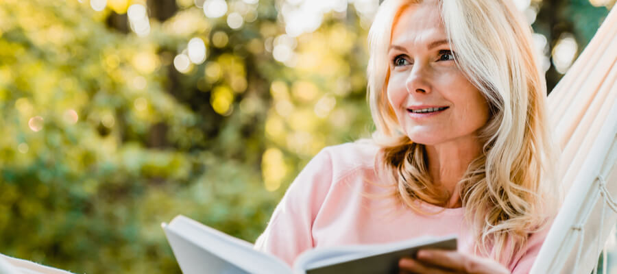 older-woman-reading-book-and-smiling