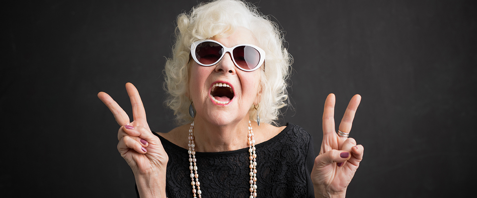 Fashion grandmother wearing white sunglasses, pearls and a black dress
