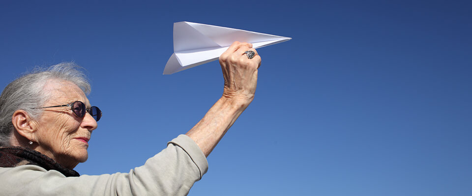 An older woman holding a paper airplane