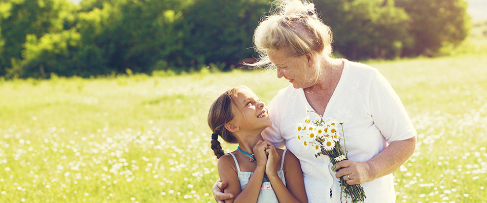 A grandmother holding a bouquet of daisies with her granddaughter
