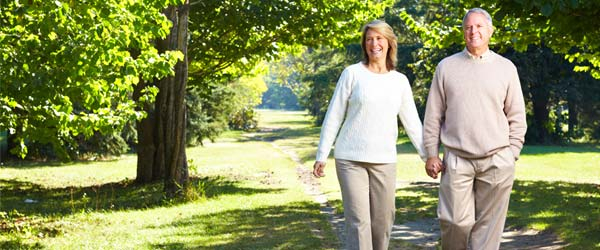 Smiling senior Canadian couple walking in a park and discussing what is a reverse mortgage.