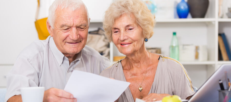 Happy Senior Spouses looking at Bills on Laptop