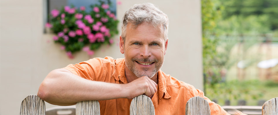 Canadian homeowner leaning on a fence and considering home equity management options like sale and leaseback.