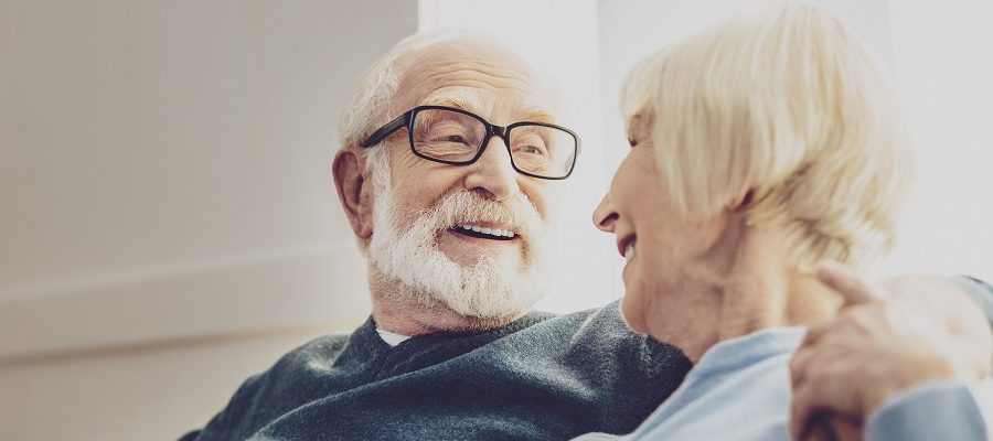 An older man looking at his wife with his arm wrapped around her