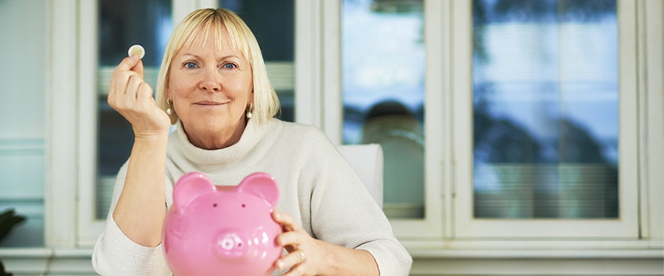 Older woman with a piggy bank, concerned about the recent federal budget and how it affects the financial health of retirees.