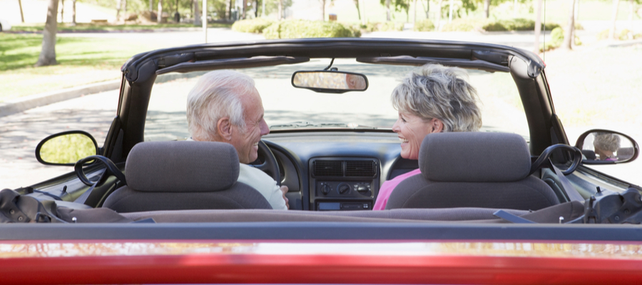 Senior couple sitting in a convertible car smiling together