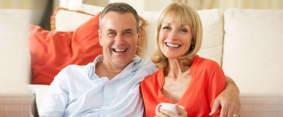 Senior couple relaxing in their living room, satisfied that they utilised the funds from their CHIP reverse mortgage in Canada.