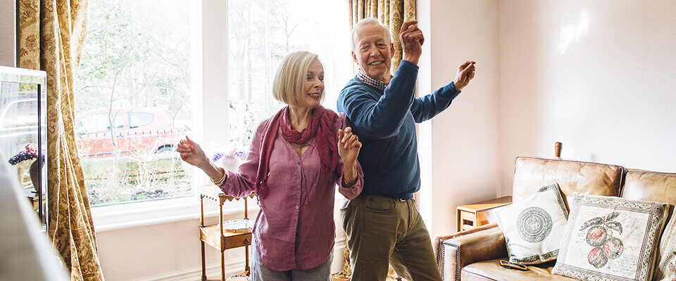 An older couple dancing in their living room together